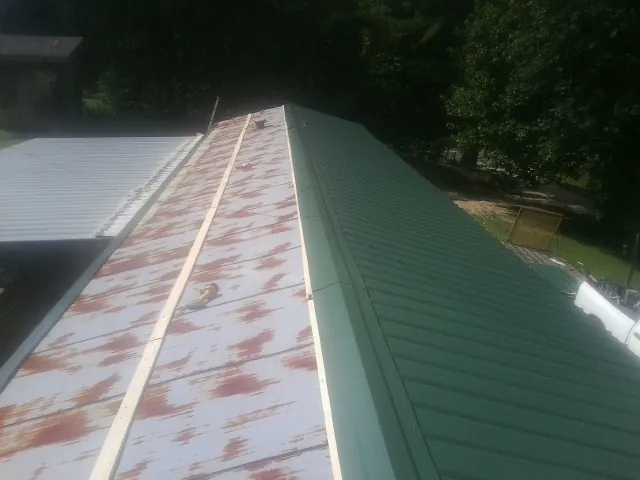 Old rusted panels beside newly installed green metal roofing — Wind Damage Roof Repair by Roofing Brothers in Effingham