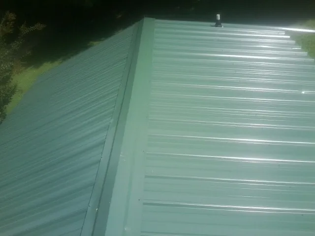 New green metal panels meeting at the ridge of a roof — Flat Roof Repair work by our crew in Effingham