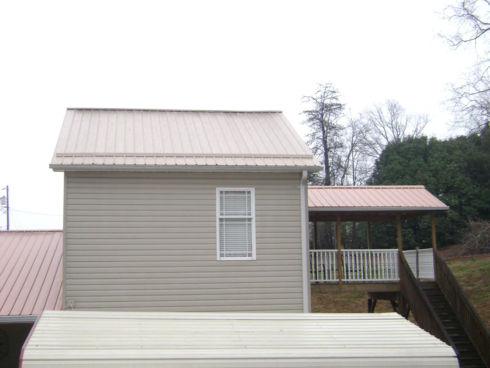 Tan metal roofs on a two story addition and attached porch, from a Roof Replacement job in Effingham